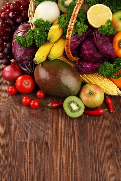 A set of fruit and vegetables in a basket on wooden background