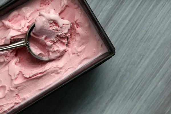 Homemade ice cream in frozen metallic container on wooden background