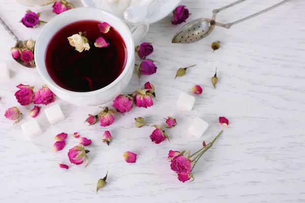 Tea and tea rose flowers on table closeup