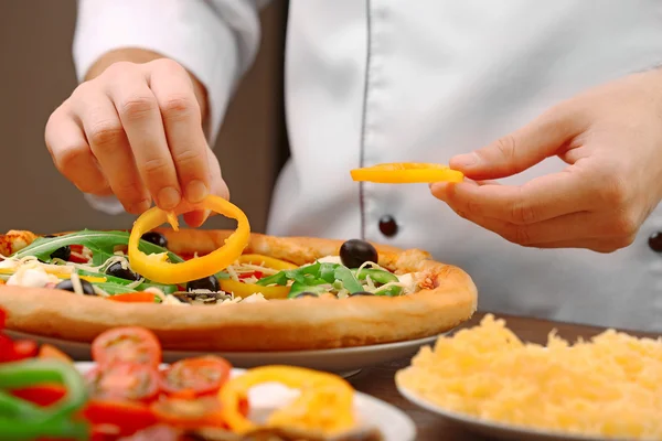 Cook making delicious pizza