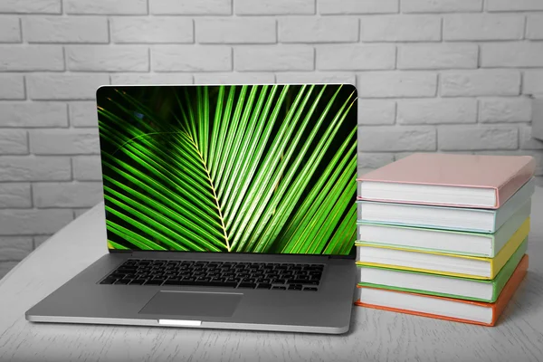 Laptop with books on wall background