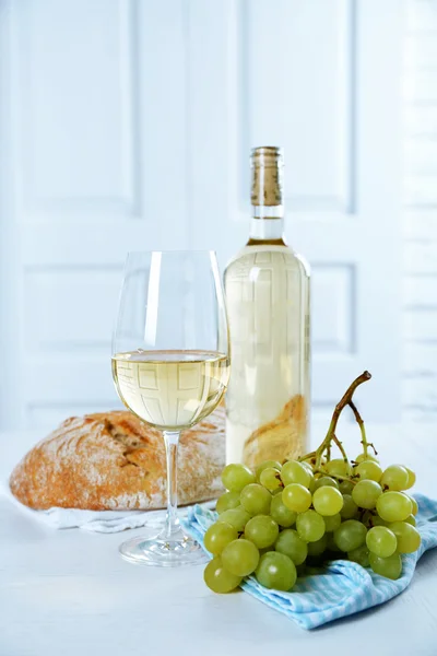 Still life of wine, grape and bread on light background