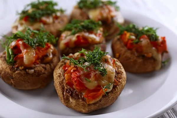 A plate with stuffed mushrooms on wooden background, close-up
