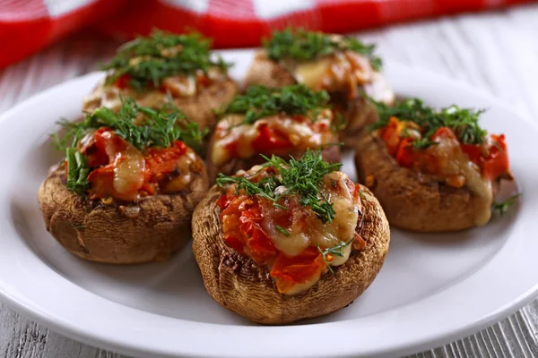 A plate with stuffed mushrooms on wooden background