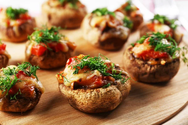 A wooden tablet with stuffed mushrooms on the table, close-up