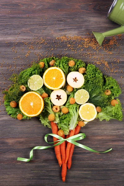 Beautiful designed bouquet of fruits and vegetables on wooden background