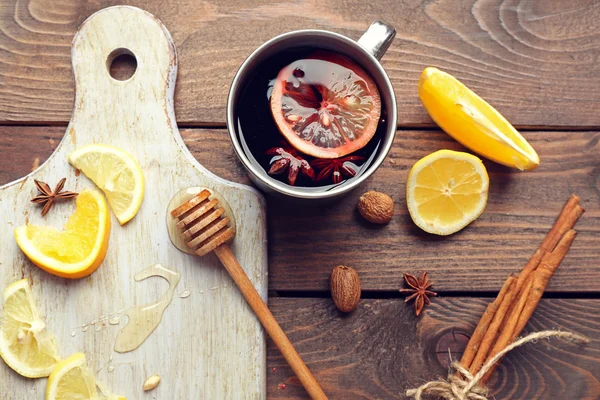Composition of mulled wine, cinnamon and citrus on wooden background