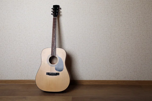 Acoustic guitar against wall