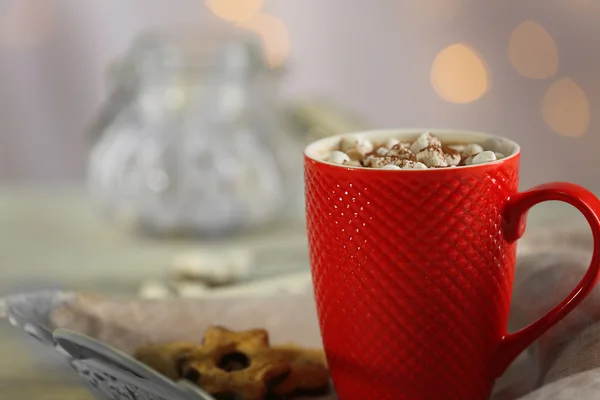 A cup of tasty cocoa and marshmallow on blurred background