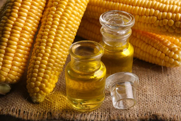 Fresh corn with bottles of oil
