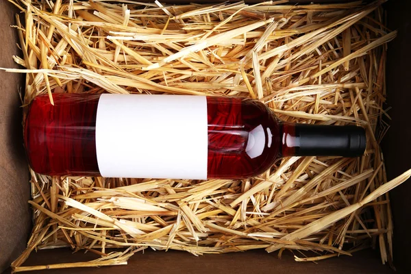 Wine bottle in the box with straw