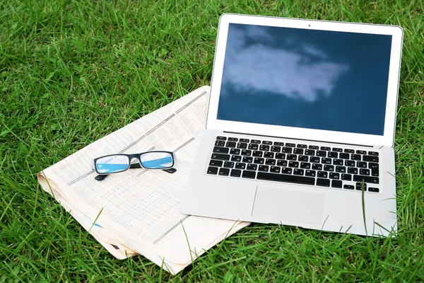 Laptop with newspaper and glasses