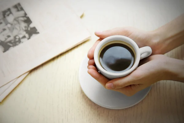 Cup of coffee with hands and newspaper on table background