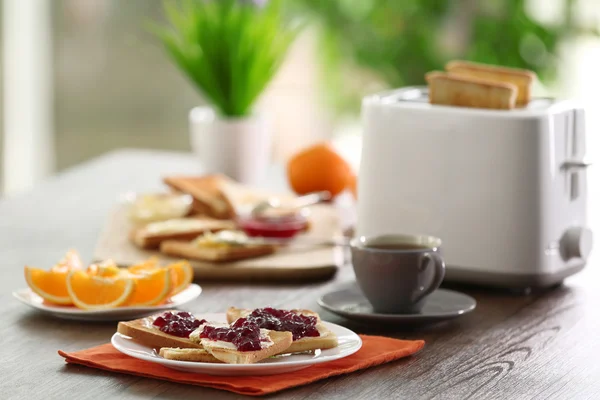 Served table for breakfast with toast, coffee and fruit, on blurred background