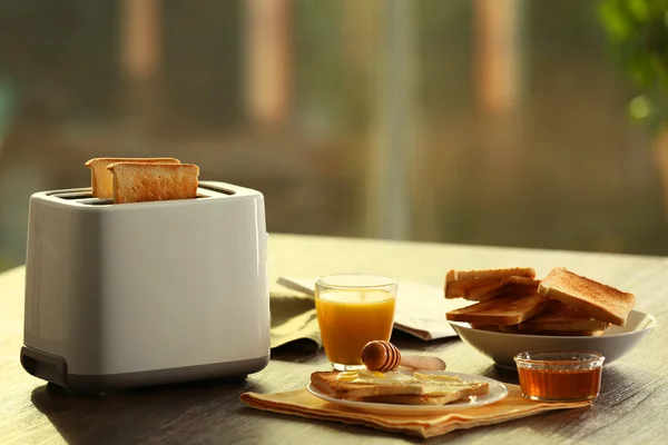 Served table for breakfast with toast and orange juice, on blurred background