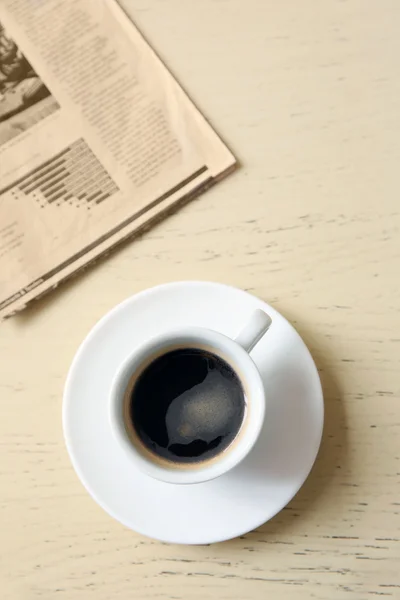 Cup of tasty coffee with newspaper on table