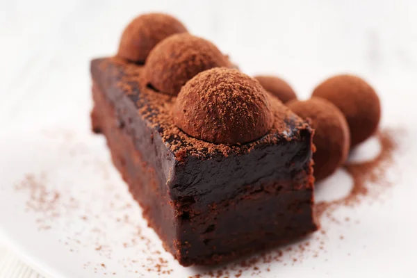 Slice of chocolate cake with a truffle on plate closeup