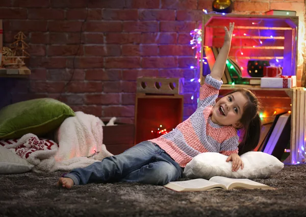 Pretty little girl with book in Christmas decorated room