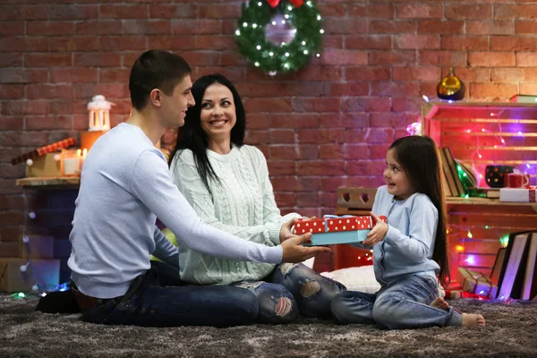 Parents give present to the daughter in the decorated Christmas room