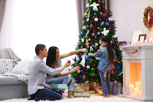Happy family decorating Christmas tree in the room