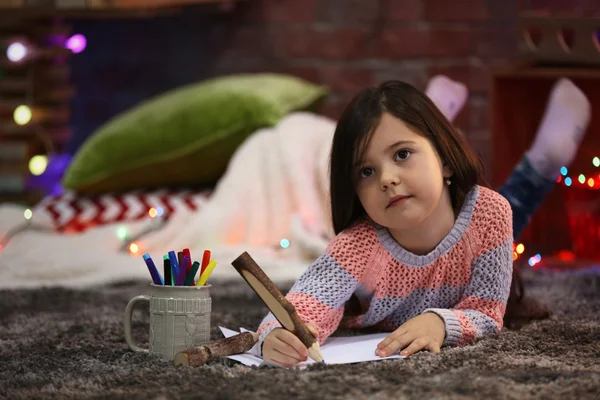 Pretty little girl painting  in Christmas decorated room