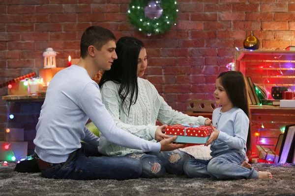 Parents give present to the daughter in the decorated Christmas room