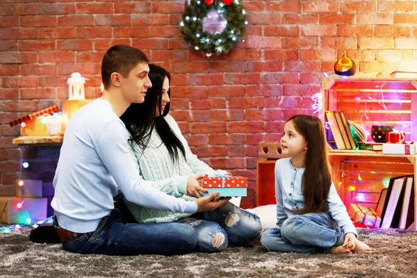Parents give present to the daughter in the decorated Christmas room