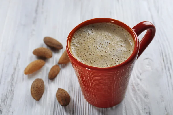 Red cup of hot cacao and nuts on wooden background