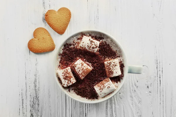 Cup of hot cacao with marshmallow and heart shaped cookies on cotton serviette, close up