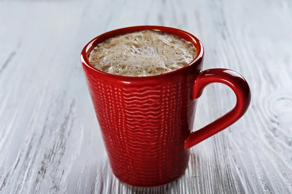 Red cup of hot cacao on wooden background