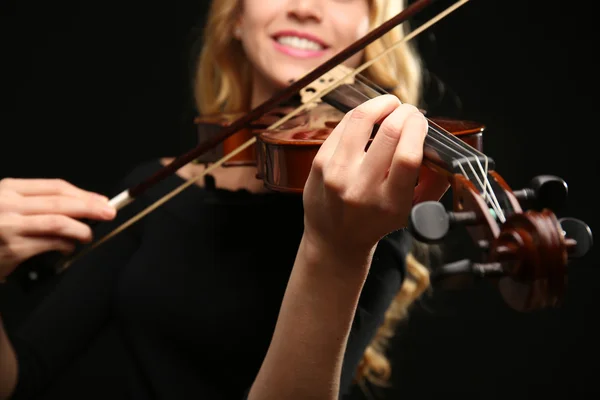 Musician plays violin on black background, close up