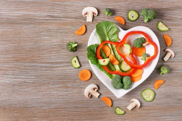 Useful cut vegetables on a plate in the form of heart