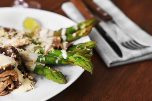 Delicious dish with asparagus and mushrooms on served wooden table in the restaurant, close up