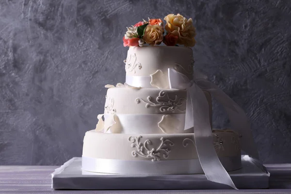 Wedding cake decorated with flowers on grey background
