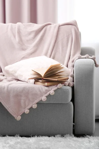 Opened book on comfortable sofa against window in the room