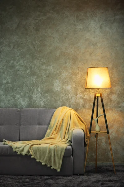 Comfortable sofa and lamp on grey wall background