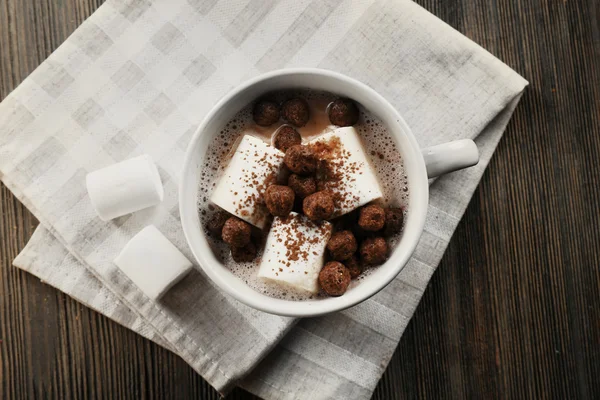 Cup of hot cacao with marshmallow on cotton serviette, close up