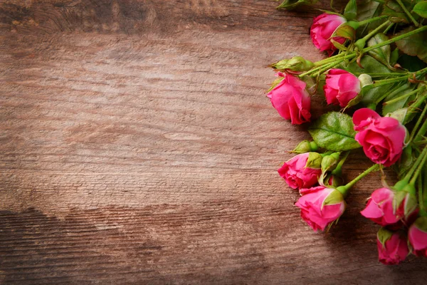 Beautiful bouquet of pink little roses on wooden background, copy space