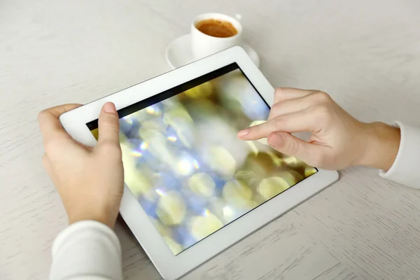 Woman using digital tablet on table close up