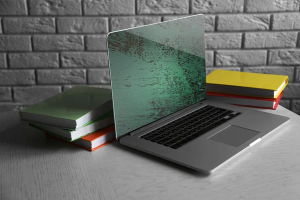 Laptop with books on wall background