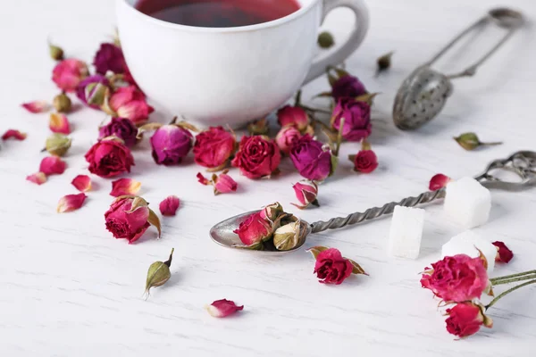 Tea and tea rose flowers on table closeup