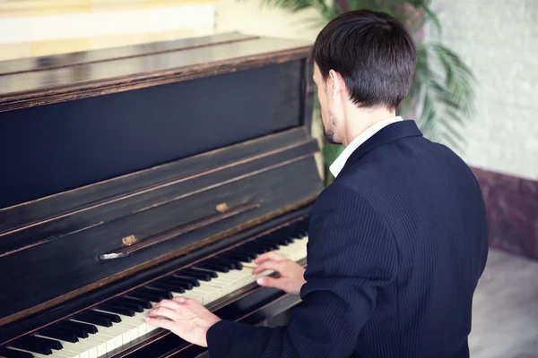 Man in black suit plays piano