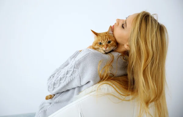 Young woman with red cat sitting on chair against white background, close up
