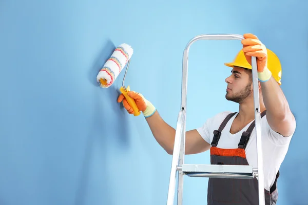 Young worker renewing apartment on wall background