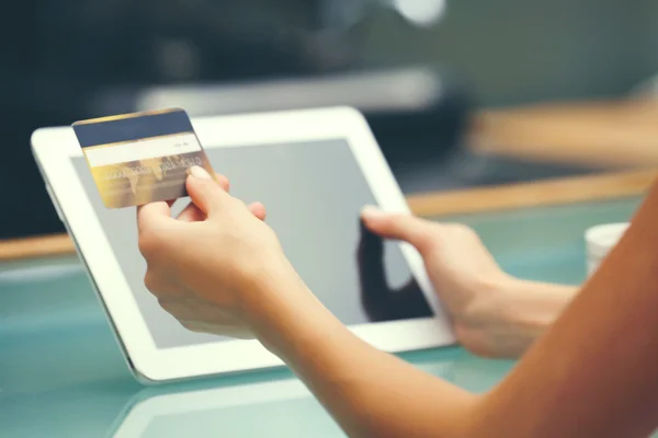 Female hands holding credit card with digital tablet on table close up