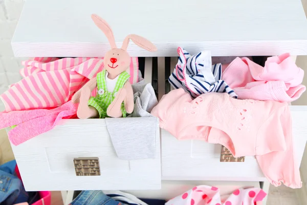 Child clothes in wooden chest of drawer, close up