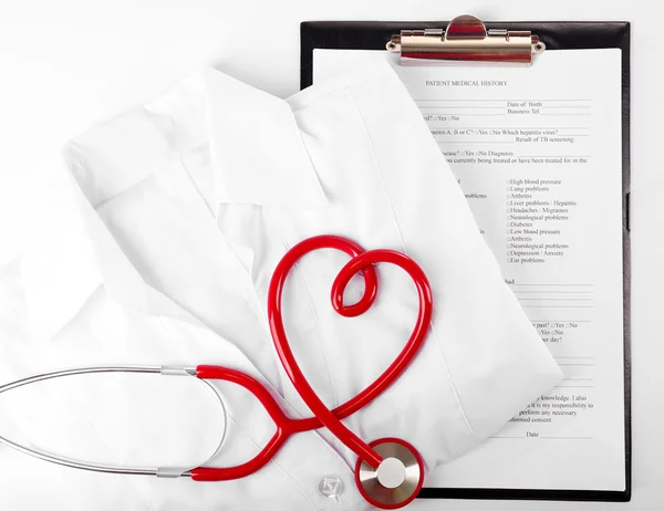 Red stethoscope, medical record and uniform on white background