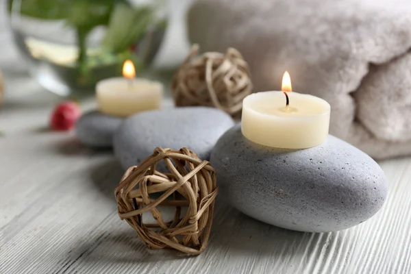 Composition of flowers, candles and stones on white wooden background, in spa salon