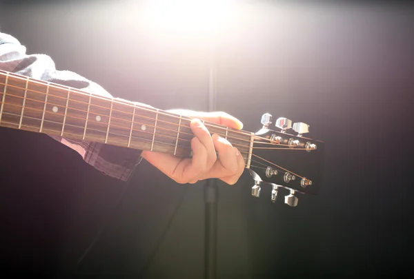 Guitars neck in musician hands on dark background, close up
