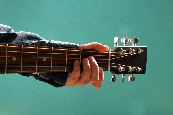 Guitars neck in musician hands on blue background, close up